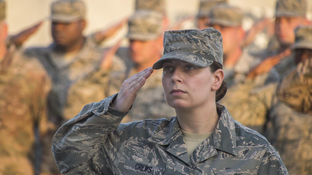 An airman salutes the American flag during a ceremony to honor the fallen.