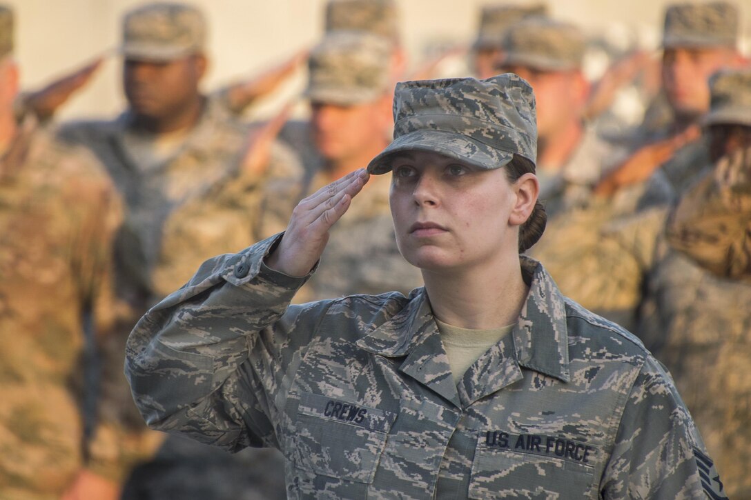 An airman salutes the American flag during a ceremony to honor the fallen.