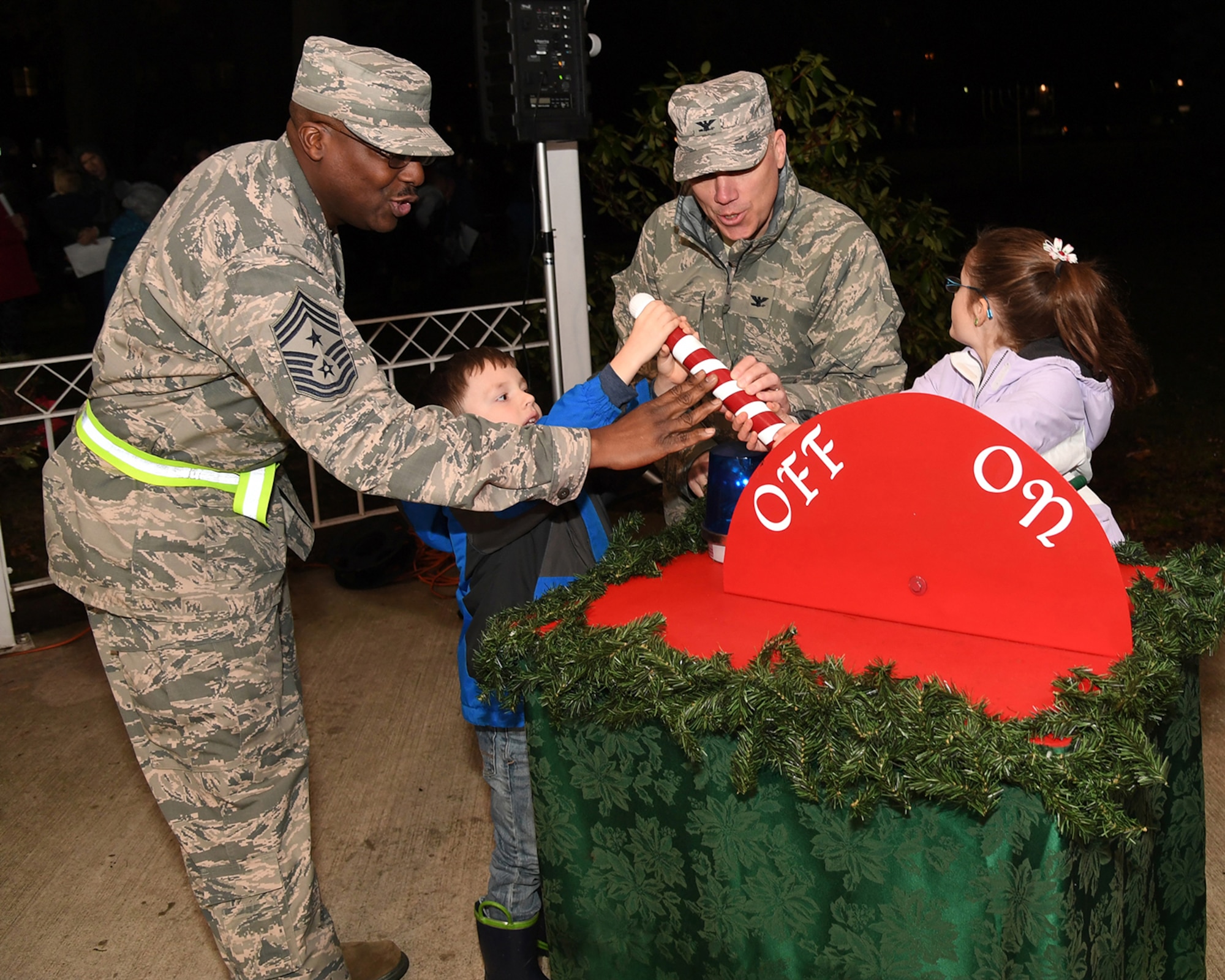 (Left to right) Chief Master Sgt. Henry L. Hayes, Hanscom's command chief, Hunter Kircher, Col. Roman L. Hund, installation commander, and Alexandria Kircher flip the switch to light Hanscom's Christmas tree outside the base chapel Dec. 5.