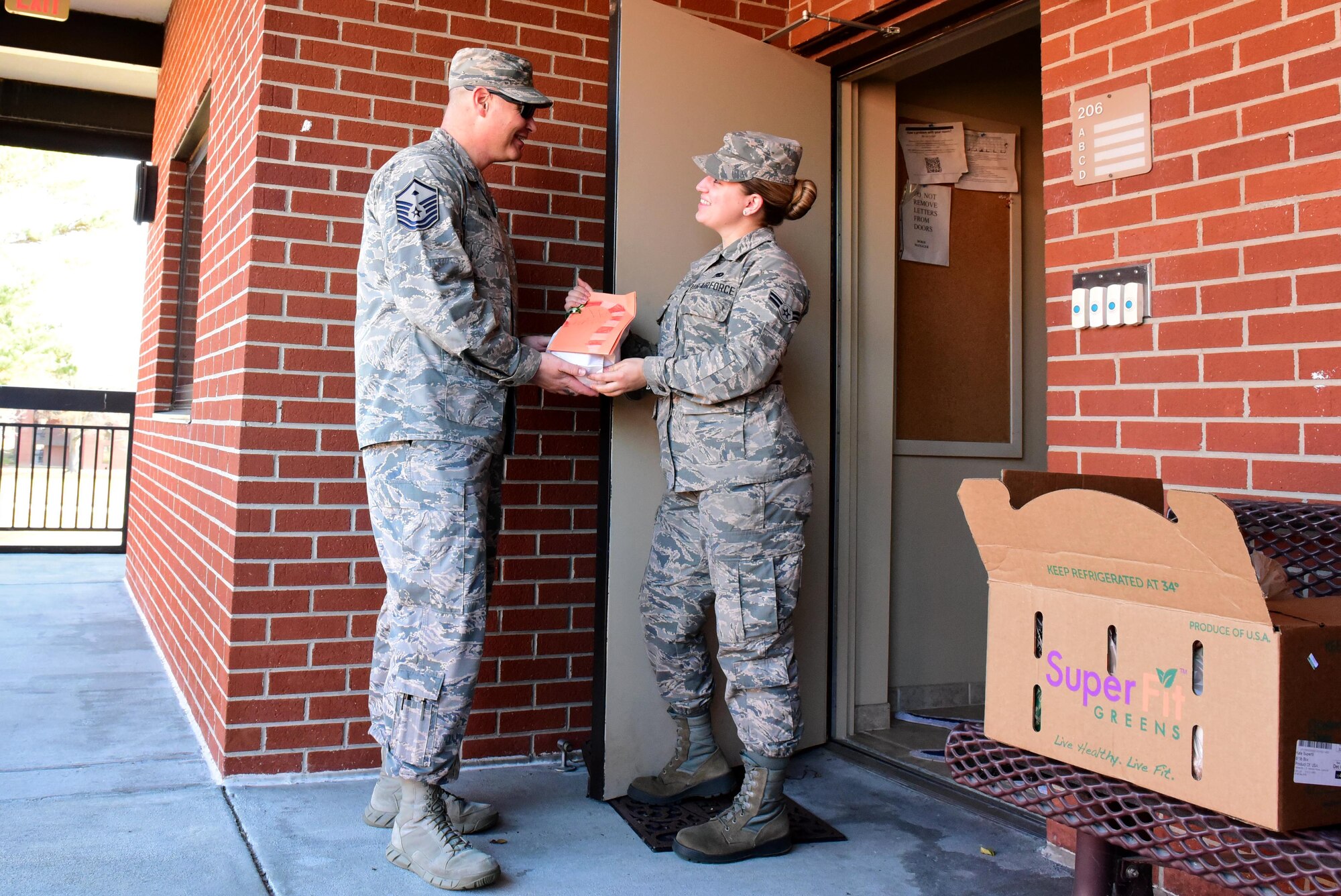 Master Sgt. Christopher Tamble, 4th Medical Group first sergeant, left, hands Airman 1st Class Emily Harnois, 4th Component Maintenance Squadron hydraulics technician, a holiday cookie packet during the annual Officer and Civilian Spouses Club Airmen Cookie Drive Dec. 4, 2017, at Seymour Johnson Air Force Base, North Carolina.