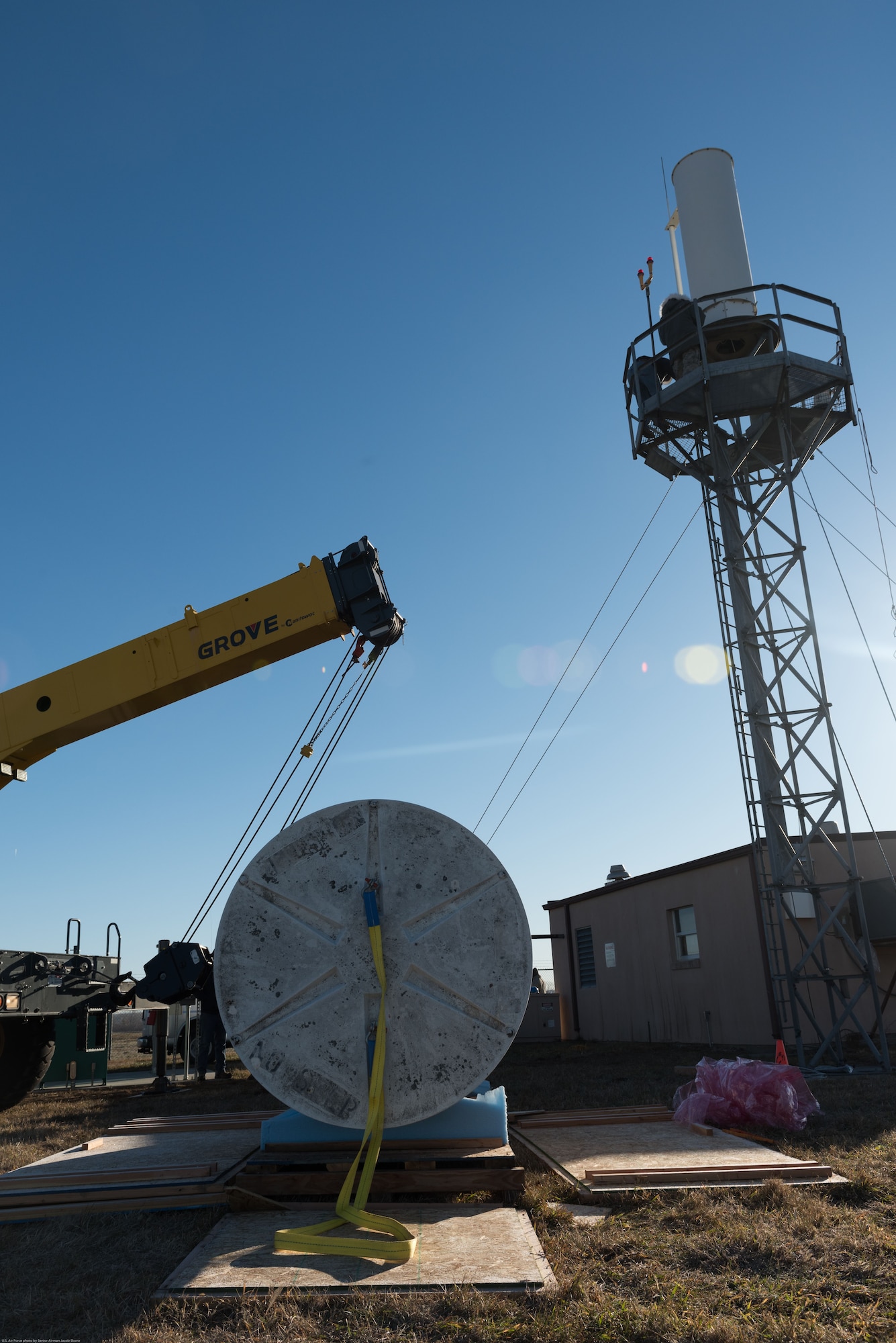 Airmen and contractors install Offutt Air Force Base’s (AFB) new Tactical Air Navigation System, background, at Offutt AFB, Nebraska, Nov. 29, 2017.