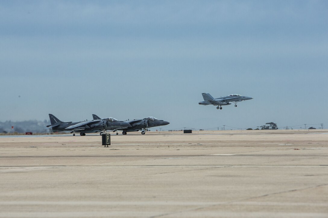 An F/A-18D Hornet, right, with Marine All-Weather Fighter Attack Squadron [VMFA(AW)] 225 takes off while two AV-8B Harrier IIs, left, with Marine Attack Squadron (VMA) 214 prepare to support missions for Exercise Winter Fury 18 at Marine Corps Air Station Miramar, Calif., Nov. 30. Winter Fury provides an opportunity for 3rd Marine Aircraft Wing to exercise the skills needed as the aviation combat element of a Marine Air-Ground Task Force during a combat deployment. (U.S. Marine Corps photo by Lance Cpl. Nadia J. Stark/Released)