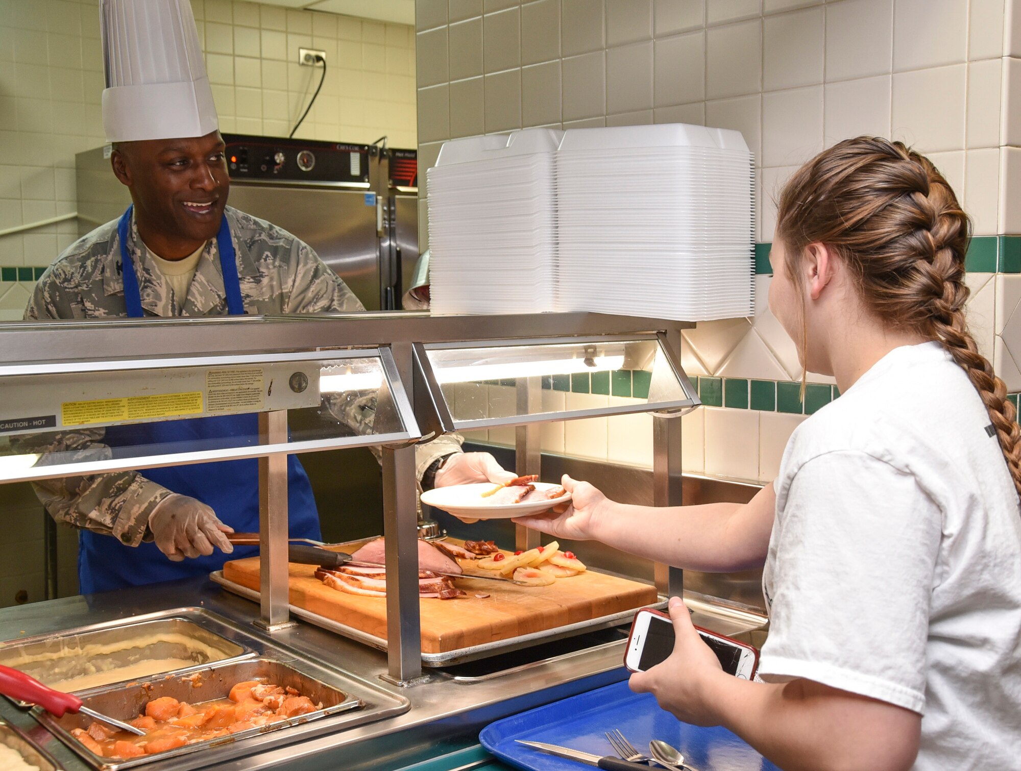 Col. Kenyon K. Bell, 72nd Air Base Wing commander, serves up a plate of sliced ham to a customer while serving Thanksgiving meals in the Vanwey Dining Facility Nov. 23, 2017, Tinker Air Force Base, Oklahoma. Bell was joined by other senior officer and enlisted leaders in the holiday tradition of serving meals to troops who, by necessity of their service, are away from home.