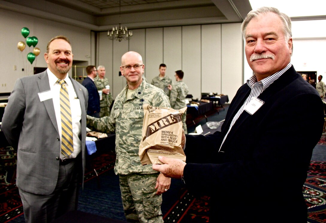 Honorary commanders representing communities around the Scott Air Force Base area came out to interact with 932nd Airlift Wing leadership on Nov. 29, 2017.  Honorary commanders are civic leaders matched up to various wing and group commanders at the base units. They serve that role throughout the year, representing various towns around the Scott Air Force Base area. Several 932nd honorary commanders came out to interact with base and 932nd Airlift Wing leadership recently. Pictured here at center is the 932nd Mission Support Group Interim Commander, Lt. Col. Wayne Johnson, who helped the visitors with cooking tips discussions as his MSG honorary commander at left, Paul Evans, of Evans Law Firm, listens to ideas. At far right, John Marquart, representing the Village of Shiloh, checks out the "Menu #4, with spaghetti" MRE or Meal Ready to Eat. The visit included a briefing of base functions and a bus ride to the simulated deployment line with additional presentations and an MRE lunch competition. (U.S. Air Force photo by Lt. Col. Stan Paregien)