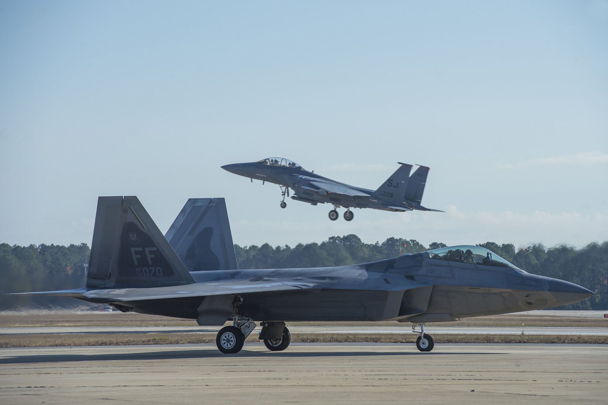 A U.S. Air Force F-22 Raptor assigned to the 94th Fighter Squadron taxis into a designated parking space while another takes off at Shaw Air Force Base, S.C., Nov. 29, 2017. The F-22s spent time at Shaw in order to certify the newest member of the F-22 Raptor Demonstration Team, U.S. Air Force Maj. Paul Lopez, F-22 Raptor Demonstration Team pilot. (U.S. Air Force photo by Staff Sgt. Zade Vadnais)