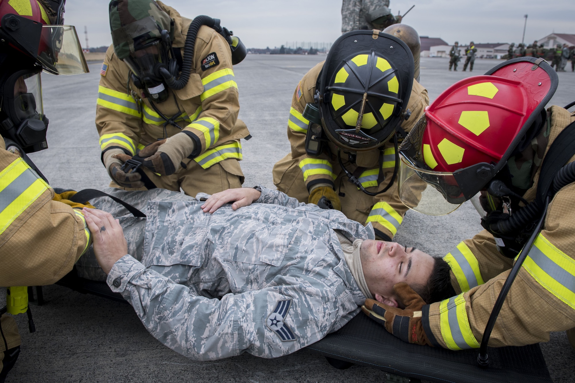 A simulated injured service member is secured on a stretcher by 374th Civil Engineer Squadron firefighters during exercise Beverly Morning 17-08 in conjunction with exercise Vigilant Ace 18, Dec. 4, 2017, at Yokota Air Base, Japan.