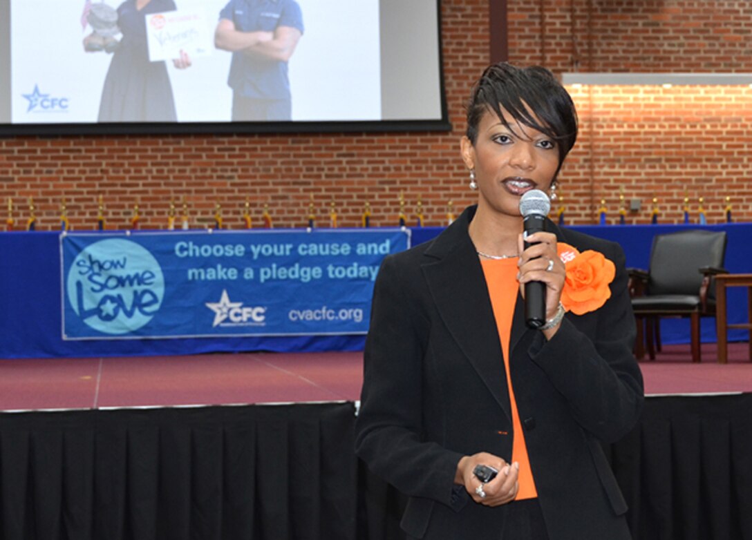 Melanie Holden holds a microphone and speaks to the audience at the DSCR/DLA Aviation Combined Federal Campaign Kick-Off.