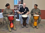 Two Marines play drums with a man.