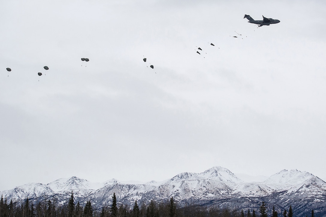 Soldiers jump from a C-17 Globemaster III aircraft while conducting parachute insertion.