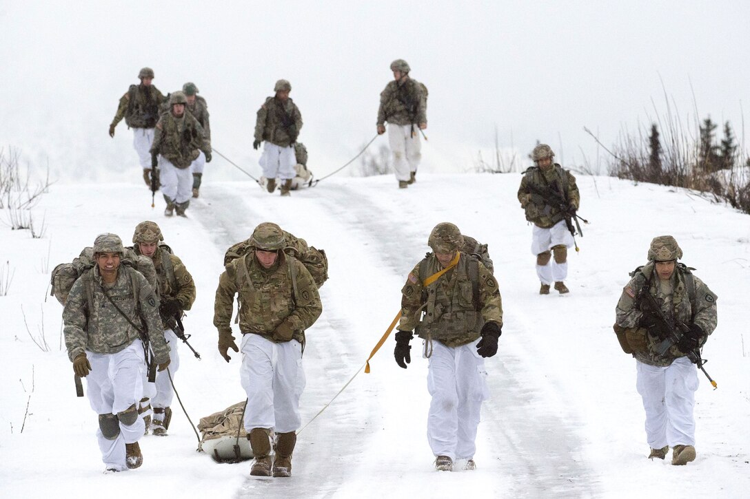 Soldiers drag stretchers with their equipment on it while participating in parachute insertion and foot patrol training.