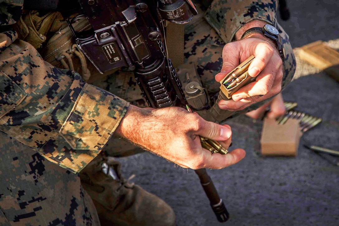 A Marine loads ammo into a magazine before prior to conducting combat marksmanship training,