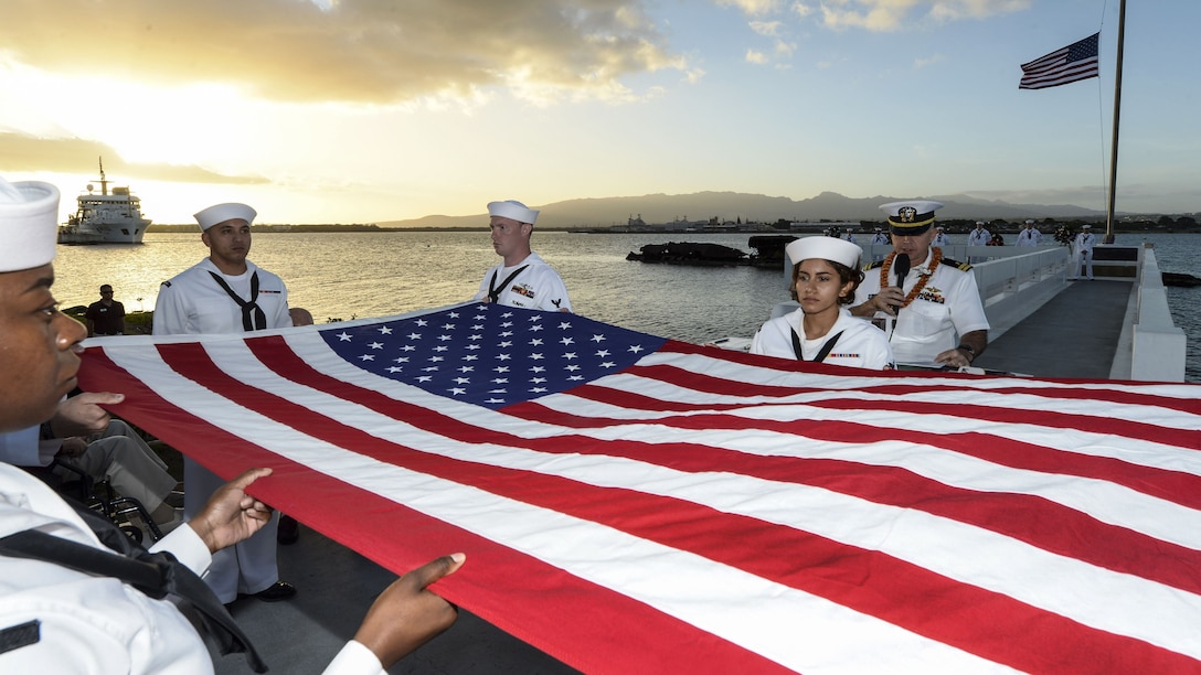 Sailors fold an American flag during a sunset ceremony in Pearl Harbor.