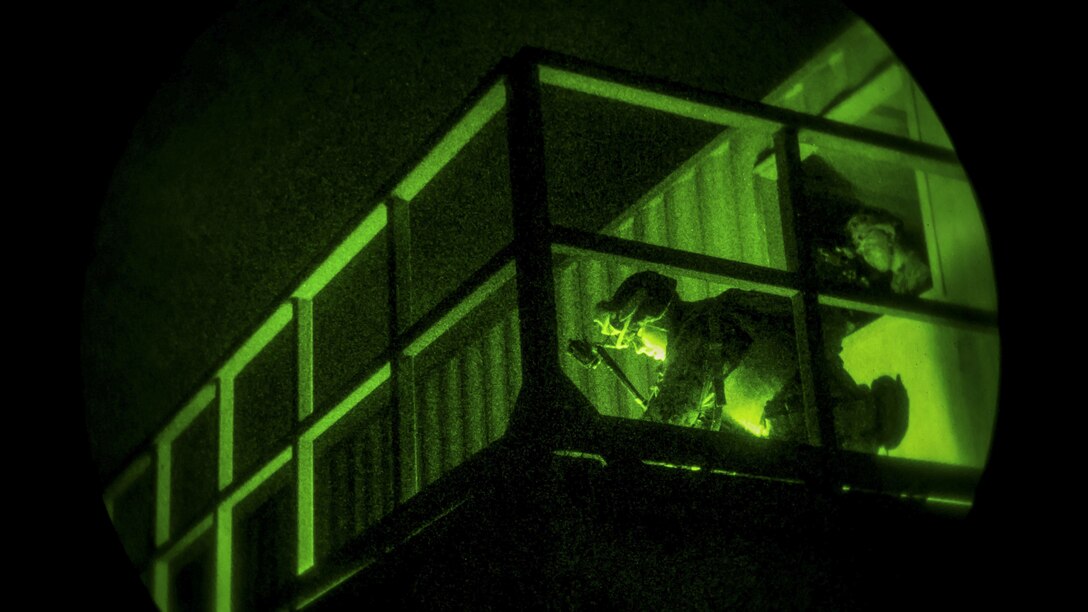 Marines conduct clearing procedures for a building at night during an exercise.