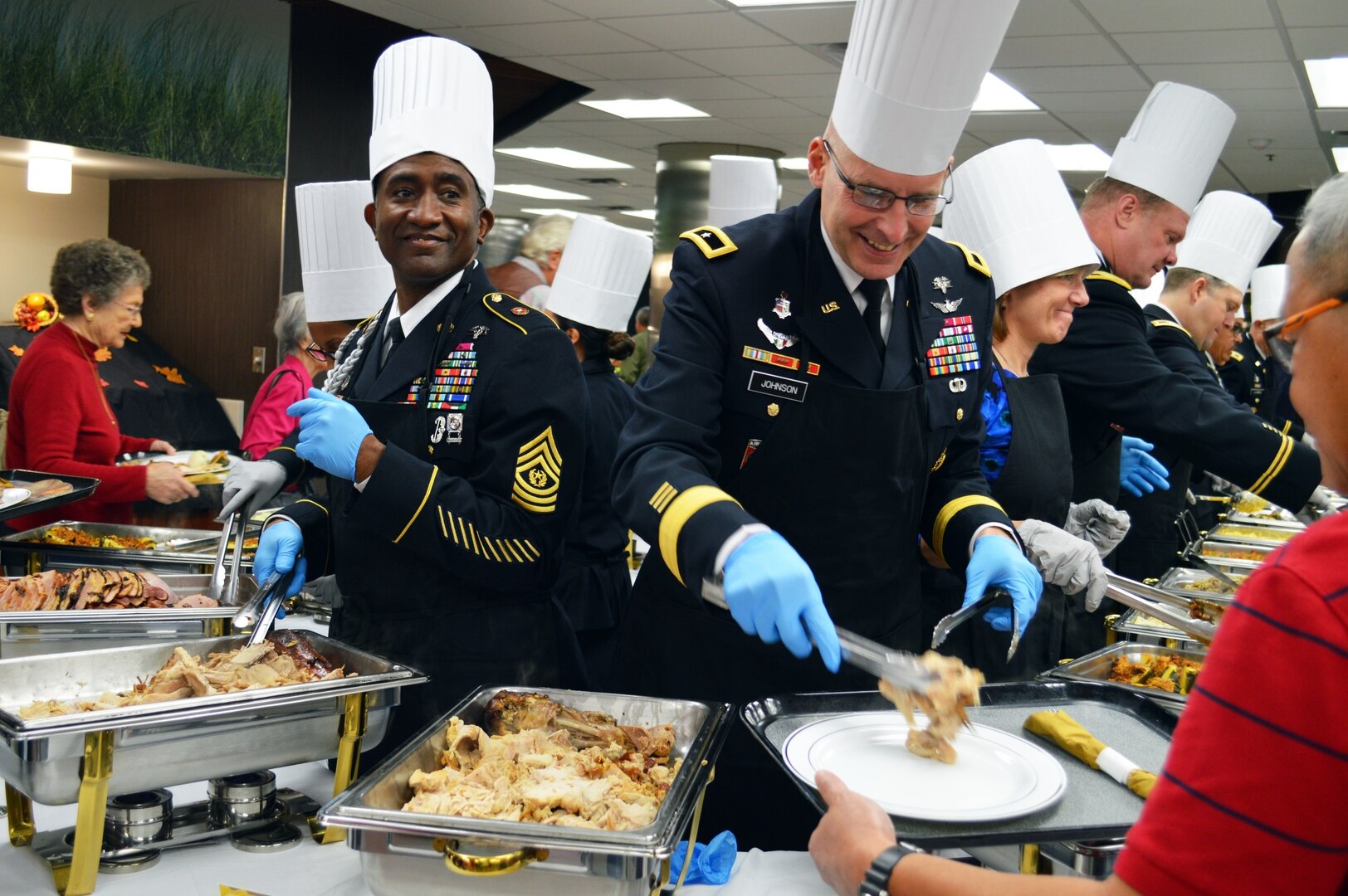 Brooke Army Medical Center commanding general Brig. Gen. Jeffrey Johnson and Command Sgt. Maj. Diamond Hough help serve Thanksgiving dinner to more than 1,000 guests Nov. 23 in the BAMC Dining Room at Joint Base San Antonio-Fort Sam Houston.