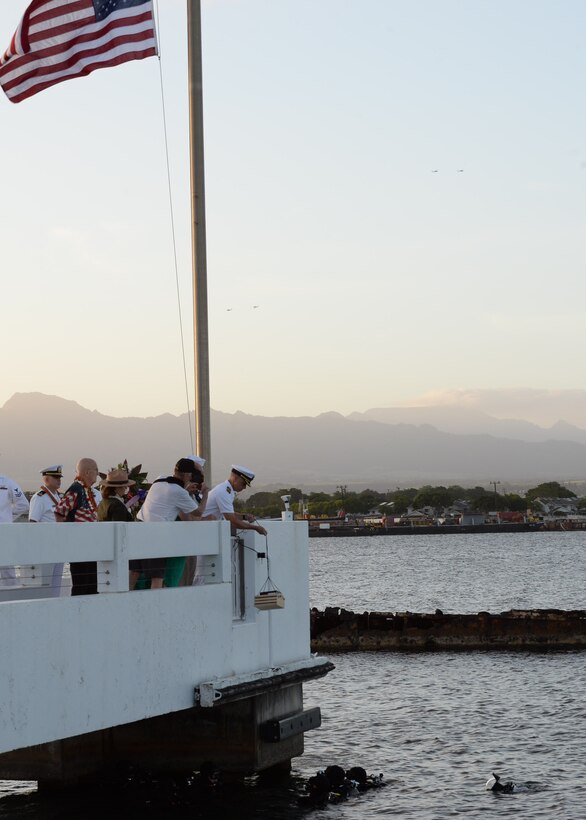 Navy Master Chief Allen Keller, command master chief for Joint Base Pearl Harbor-Hickam, Hawaii, lowers the ashes of Harry Hohstadt into the waters of Pearl Harbor during a double interment ceremony at the USS Utah Memorial.