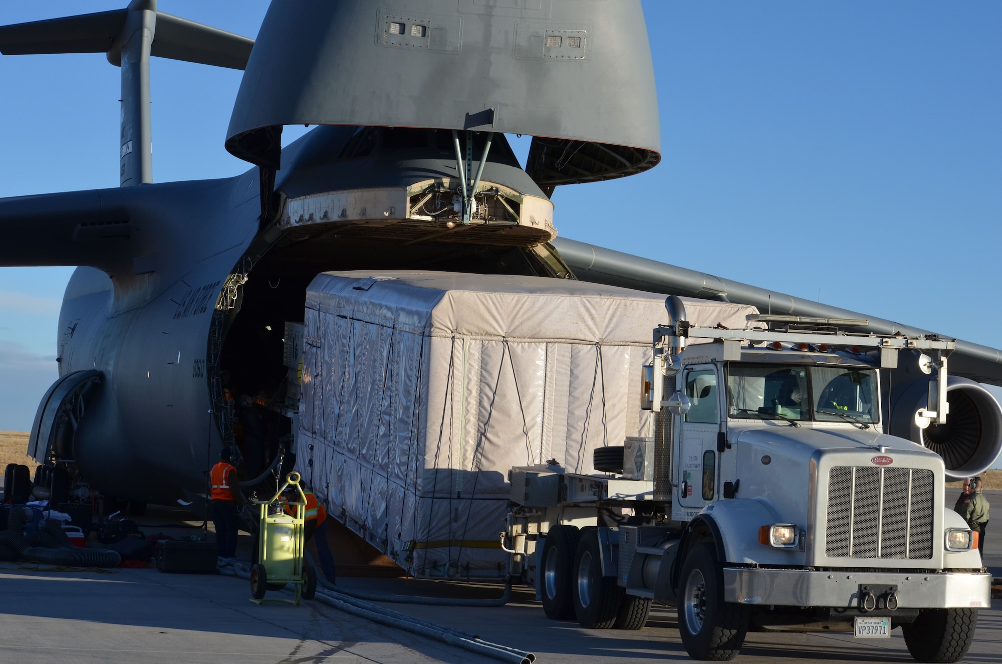 A C-5M Super Galaxy, flown by a Westover Air Reserve Base 337th Airlift Squadron crew, is seen at Buckley Air Force Base, Colo., during loading of a GOES-S weather satellite.