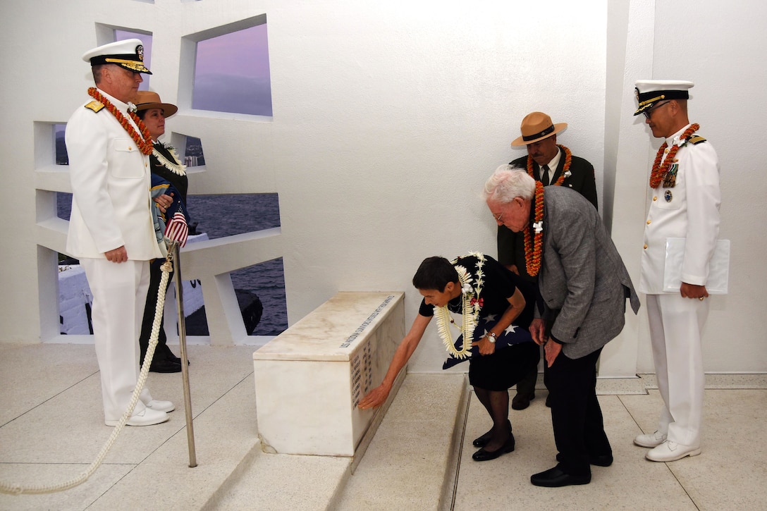 Maryan St. Claire touches her late father's name after its unveiling during an interment ceremony in his memory on board the USS Arizona Memorial.