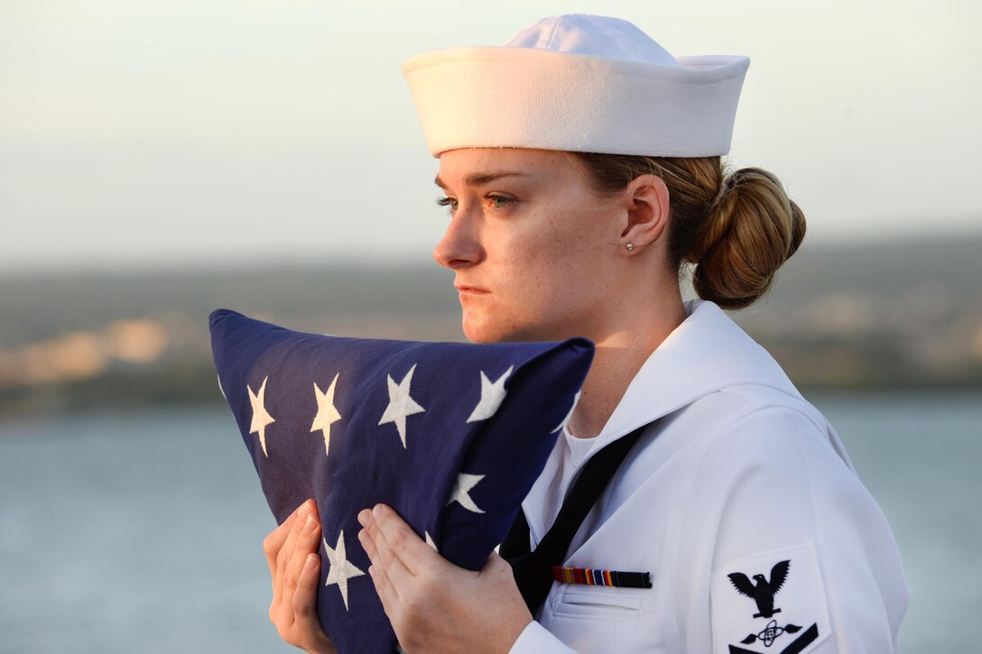 Navy Petty Officer 3rd Class Selena Colwell holds the American flag.