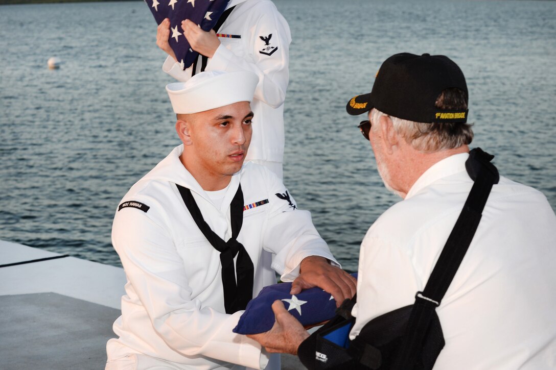 Navy Petty Officer 3rd Class Timothy Testa presents the American flag to Mark Hohstadt.