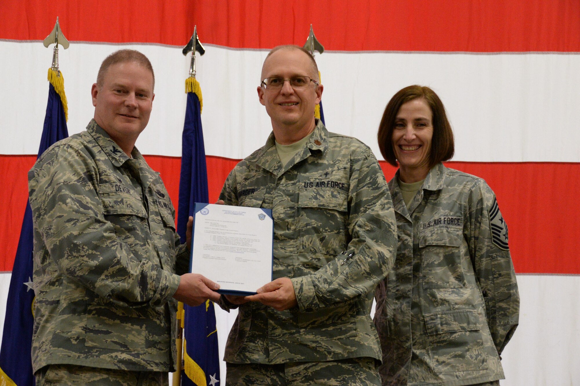 Col. James DeVere, the 302nd Airlift Wing commander, left, presents the Air Force Reserve Command 2016 Ministry of Presence Award to Chaplain (Maj.) Todd Harder, the 302nd AW chaplain, alongside Chief Master Sgt. Viki Robertson, the 302nd AW command chief, during the December Unit Training Assembly at Peterson Air Force Base, Colo., Dec. 3, 2017. The wing’s chaplain office received the award for investing more than 650 hours in unit engagement resulting in more than 2,000 points of contact supporting the Reserve wing’s Airmen. (U.S. Air Force photo/Staff Sgt. Frank Casciotta)