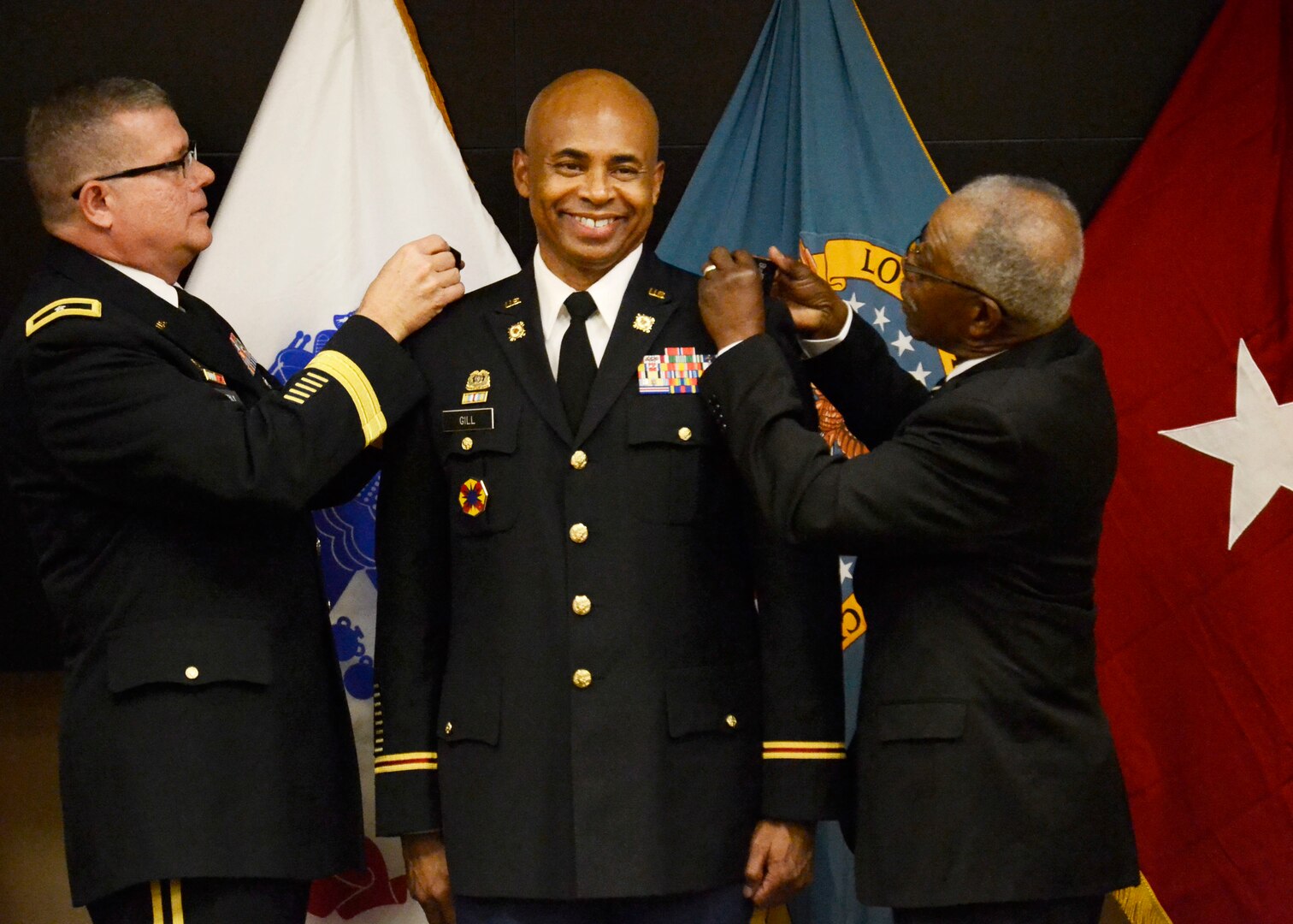 DLA Troop Support Commander Army Brig. Gen. Mark Simerly, left, places Army Col. James G. Gill’s, center, new colonel rank onto his uniform, along with Gill’s cousin Steve Peay during a promotion ceremony at DLA Troop Support in Philadelphia December 1, 2017. Gill is DLA Troop Support’s new Joint Reserves Forces team lead, joining the organization in November.