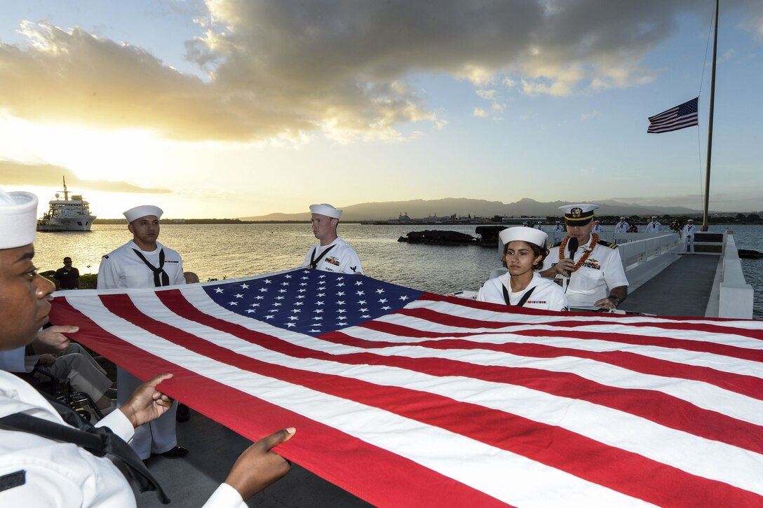 Sailors fold an American flag during a sunset ceremony in Pearl Harbor.