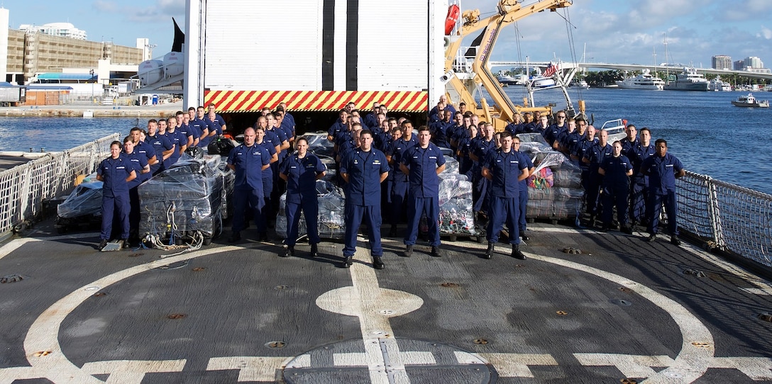 Members of the Coast Guard Cutter Escanaba crew stand next to approximately 12.4 tons of cocaine Dec. 7, 2017