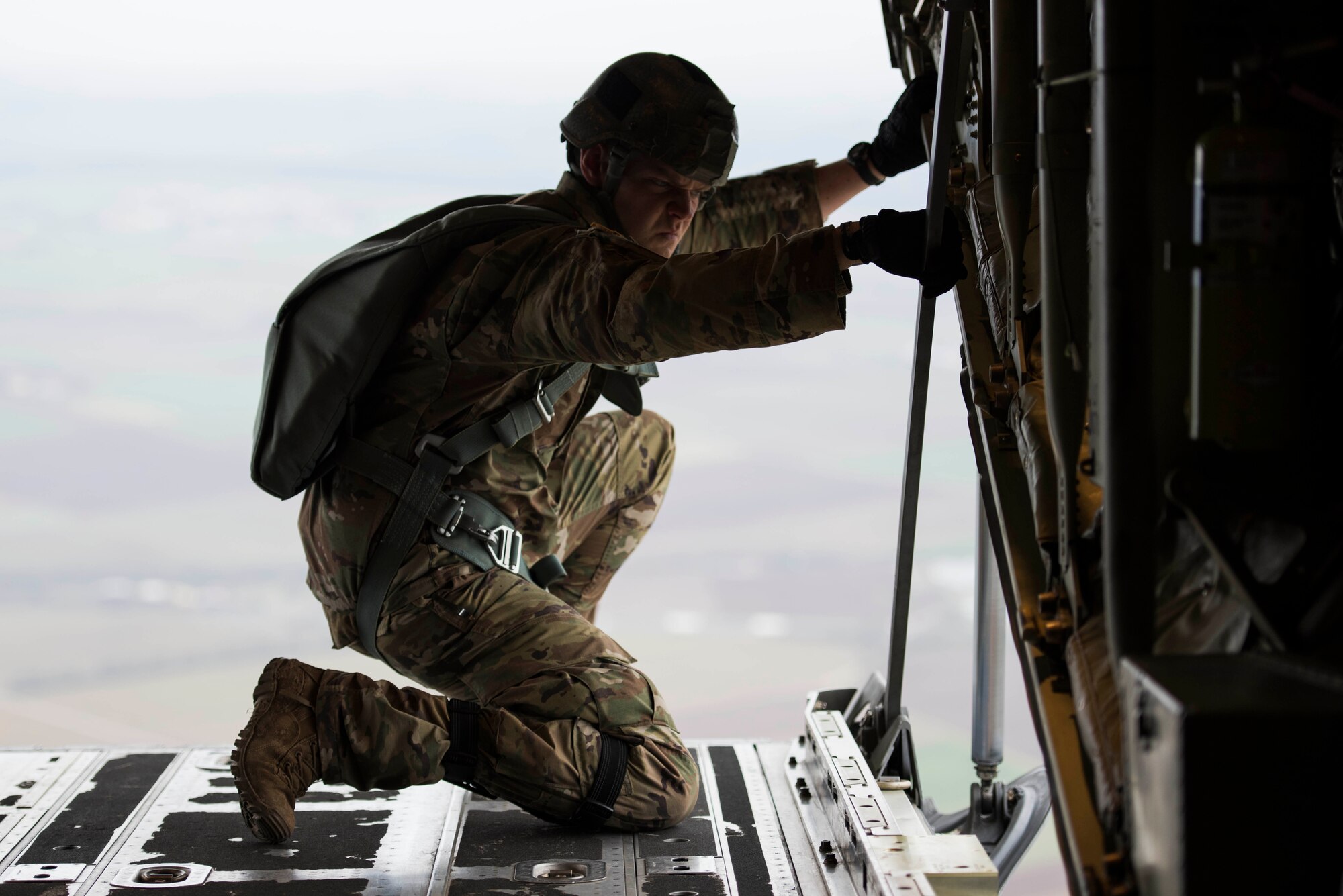 A U.S. Army jumpmaster looks out of a U.S. Air Force C-130J Super Hercules over Alzey Drop Zone, Germany, Dec. 6, 2017. The jumpmaster verified the sky conditions before giving the all clear signal to the paratroopers inside the C-130J. (U.S. Air Force photo by Senior Airman Devin M. Rumbaugh)