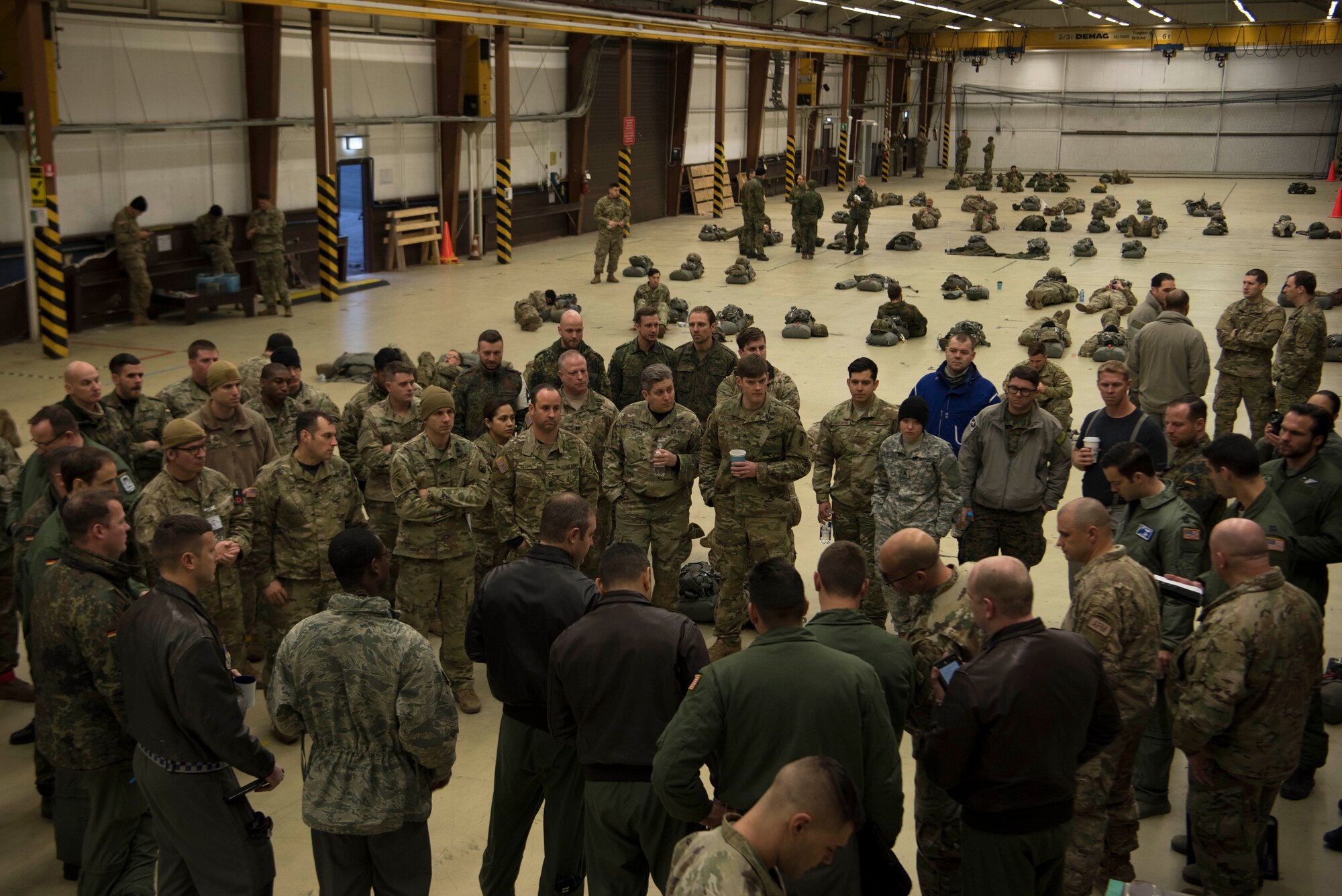 Members of the U.S. Air Force, U.S. Army, German, Italian, Dutch, British, and Estonian militaries, receive a mission brief before gearing up for Operation Toy Drop 2017 on Ramstein Air Base, Germany, Dec. 6, 2017. The paratroopers participated in Operation Toy Drop 2017 to maintain their military free fall and jump master proficiencies, and to improve NATO interoperability. (U.S. Air Force photo by Senior Airman Devin M. Rumbaugh)