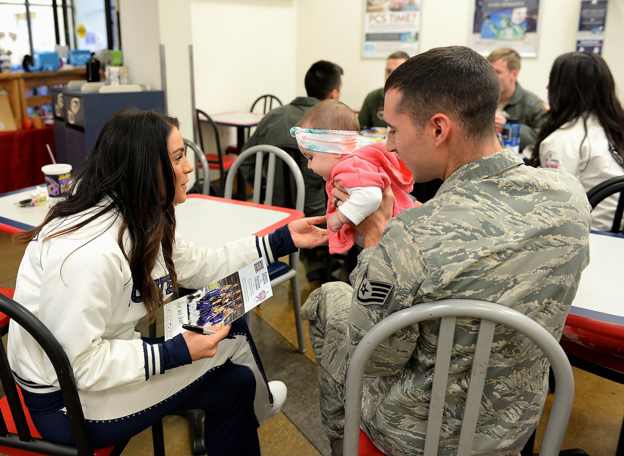 Staff Sgt. Zachary Kunkler, 14th Security Forces Squadron Military Working Dog handler, and his daughter, Emrie, speak with Kelsey, Dallas Cowboys Cheerleader, Dec. 4, 2017, at the Exchange on Columbus Air Force Base, Mississippi. The cheerleaders met with Airmen and their families throughout the day. (U.S. Air Force photo by Airman 1st Class Keith Holcomb)
