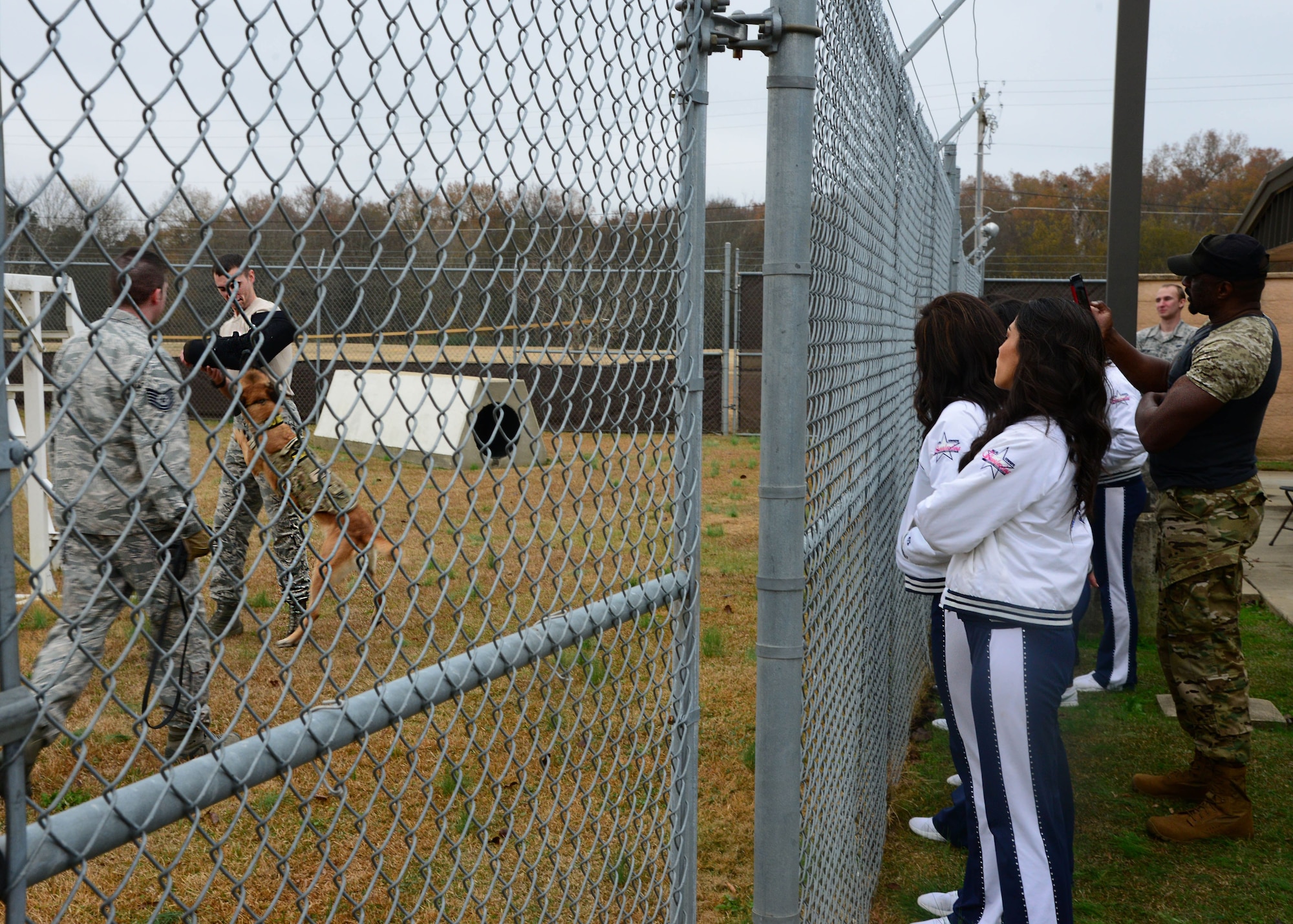 The Dallas Cowboys Cheerleading squad watches as Tech. Sgt. Karl Stenfanowicz, 14th Security Forces Squadron Kennel Master, commands Nnora, 14th SFS military working dog, to attack Staff Sgt. Zachary Kunkler, 14th SFS MWD handler, during a live demonstration Dec. 4, 2017, on Columbus Air Force Base, Mississippi. Ten members of the squad were selected to participate in a USO tour across U.S. Air Force bases throughout the winter holidays. (U.S. Air Force photo by Airman 1st Class Beaux Hebert)