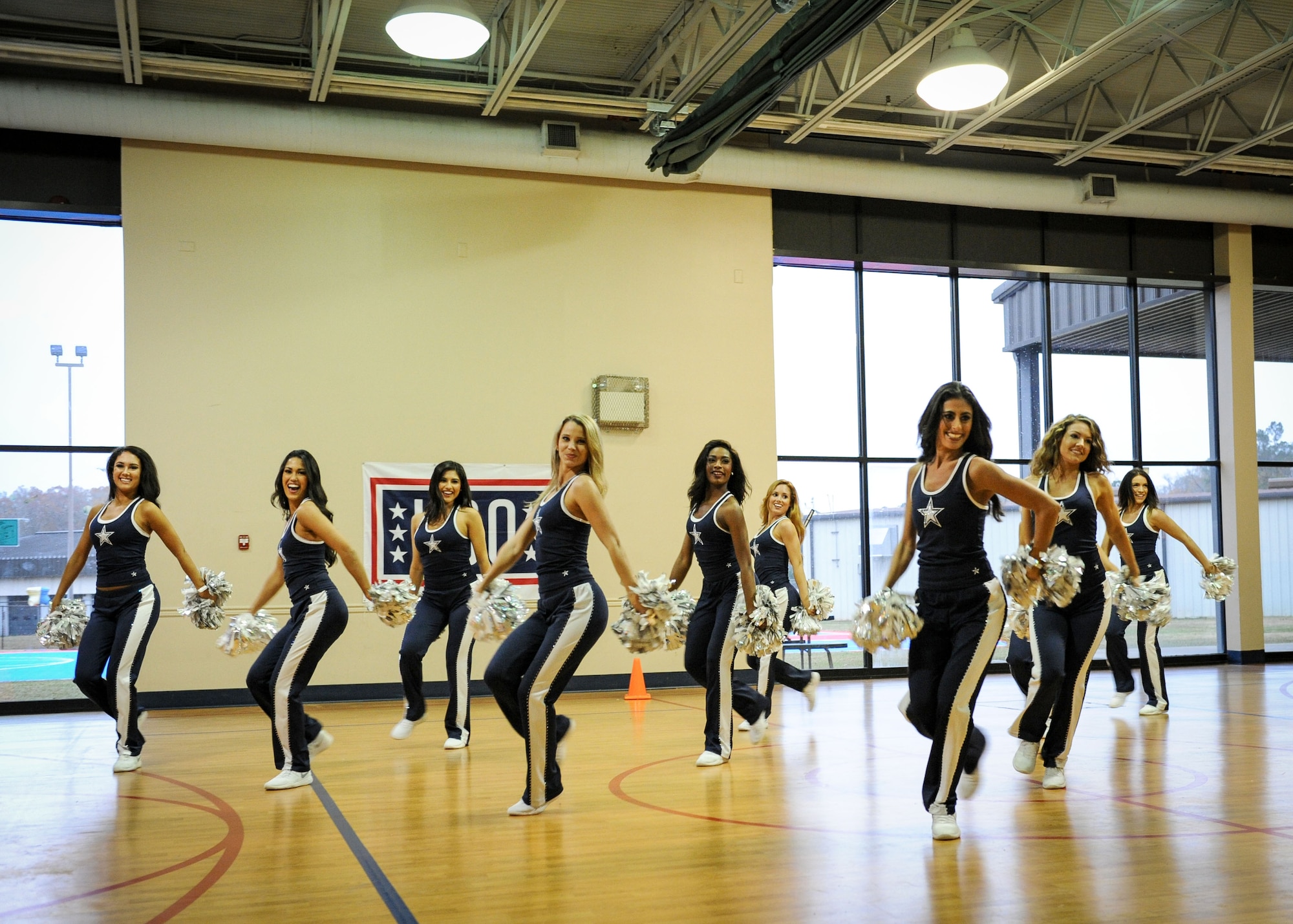 Members of the Dallas Cowboys Cheerleaders perform a routine for people at the Youth Center Dec. 4, 2017, on Columbus Air Force Base, Mississippi. Following their routine, the cheerleaders performed a Cheer to Fitness Clinic for children who attended. (U.S. Air Force photo by Staff Sgt. Christopher Gross)