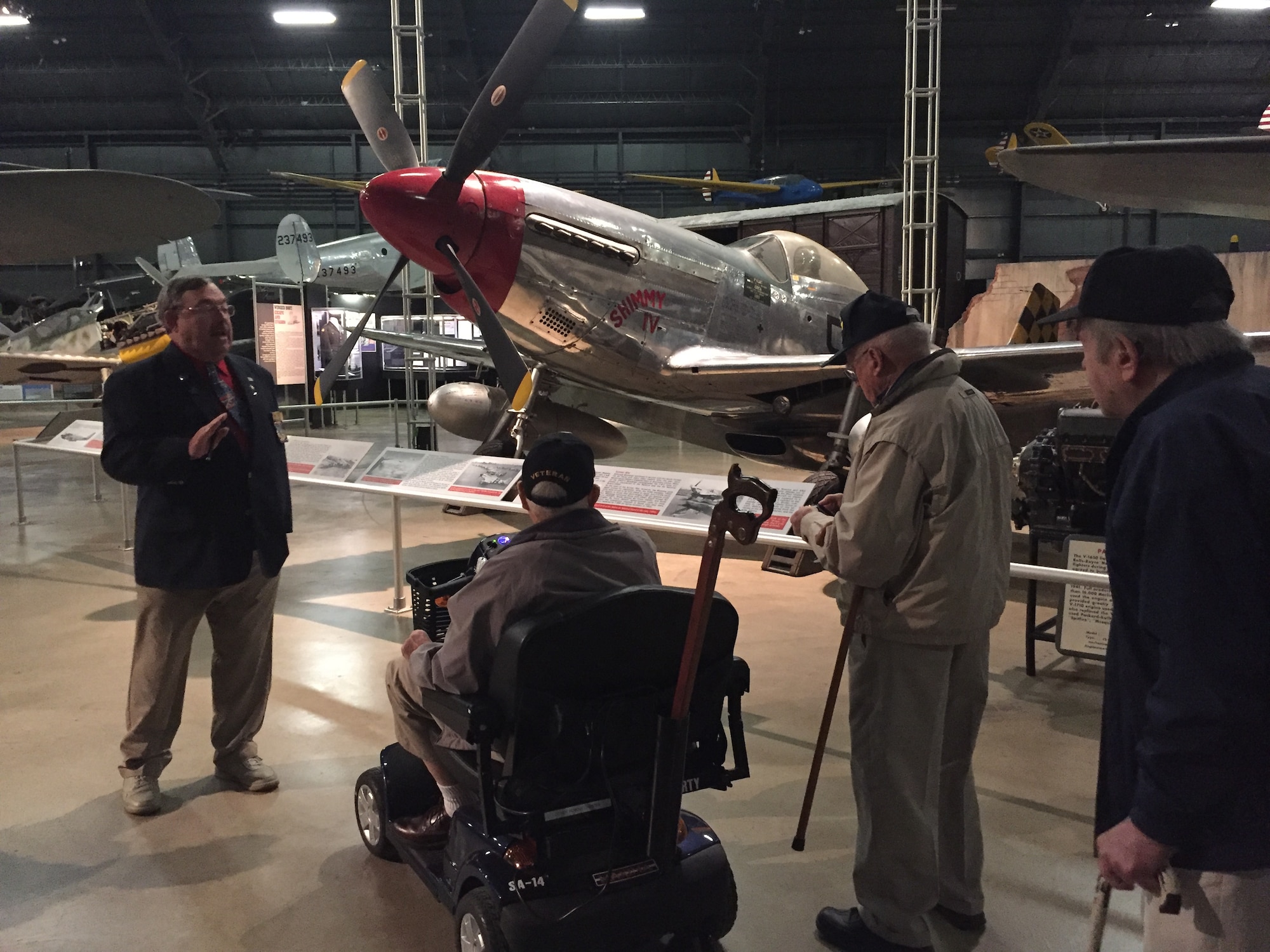 Wendell Miller, a docent at the National Museum of the U.S.Air Force, imparts facts about the North American P-51D Mustang fighter in the World War II Gallery to members of the Honoring Our Promises group Dec. 1. Eighteen area veterans enjoyed a tour and lunch, among them Larry Reynolds,WWII Army combat medic and liberator ofJewish concentration camp Gunskirchen Lager, on scooter; Air Force veteran Les Mills of Middletown; and William Wilmer, retired Air Force pilot.(Skywrighter photo/Amy Rollins)
