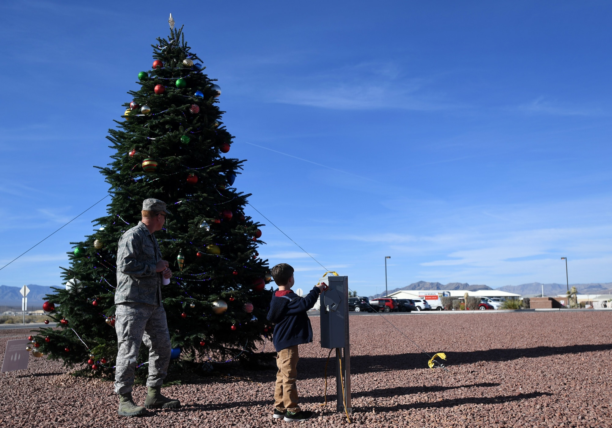 A child turns the Christmas tree lights on during the first tree-lighting ceremony Dec. 2, 2017, at Creech Air Force Base, Nev. The tree stands almost 20 feet tall and is the base’s first live Christmas tree. (U.S. Air Force photo/Senior Airman Christian Clausen)