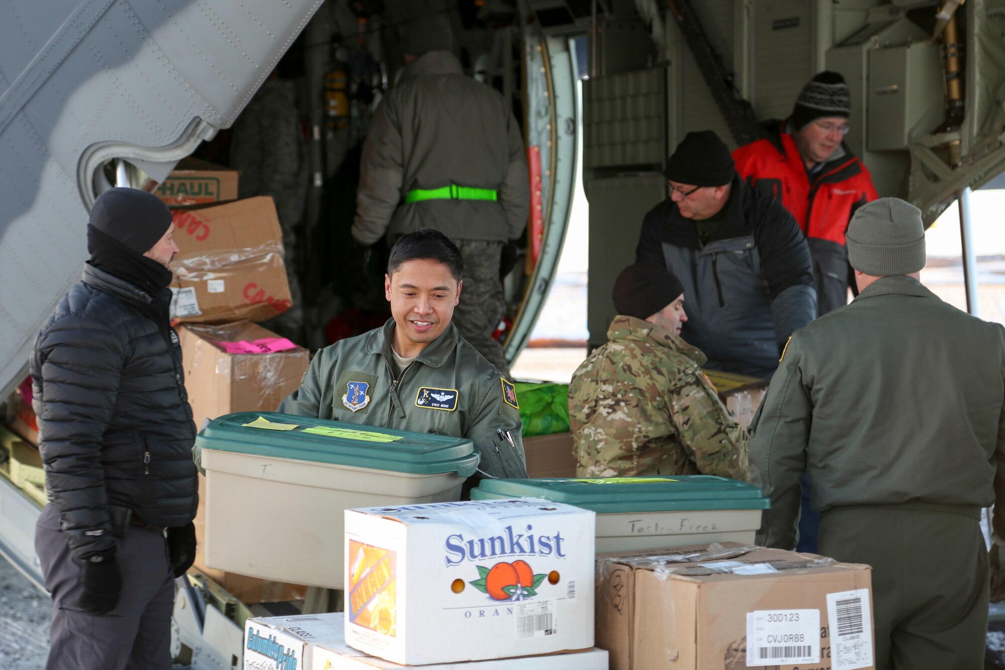Alaska Air National Guardsman Lt. Col. Eric Budd, commander of the 211th Rescue Squadron, and other National Guard and community volunteers unload an HC-130J Combat King II aircraft in St. Michael, Alaska, on Dec. 5, 2017. Operation Santa Claus is an Alaska National Guard annual community outreach program that provides Christmas gifts, books, school supplies, fresh fruit and sundaes to youngsters in rural communities. (U.S. Army National Guard photo by Staff Sgt. Balinda O’Neal Dresel)