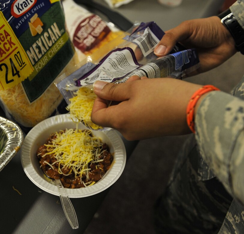 Airman 1st Class Kaylyn Carrier, right, 628th Logistics Readiness Squadron logistics planner, scoops cheese onto her chili during a dormitory dinner hosted for Airmen Dec. 6, 2017, at Joint Base Charleston, S.C.