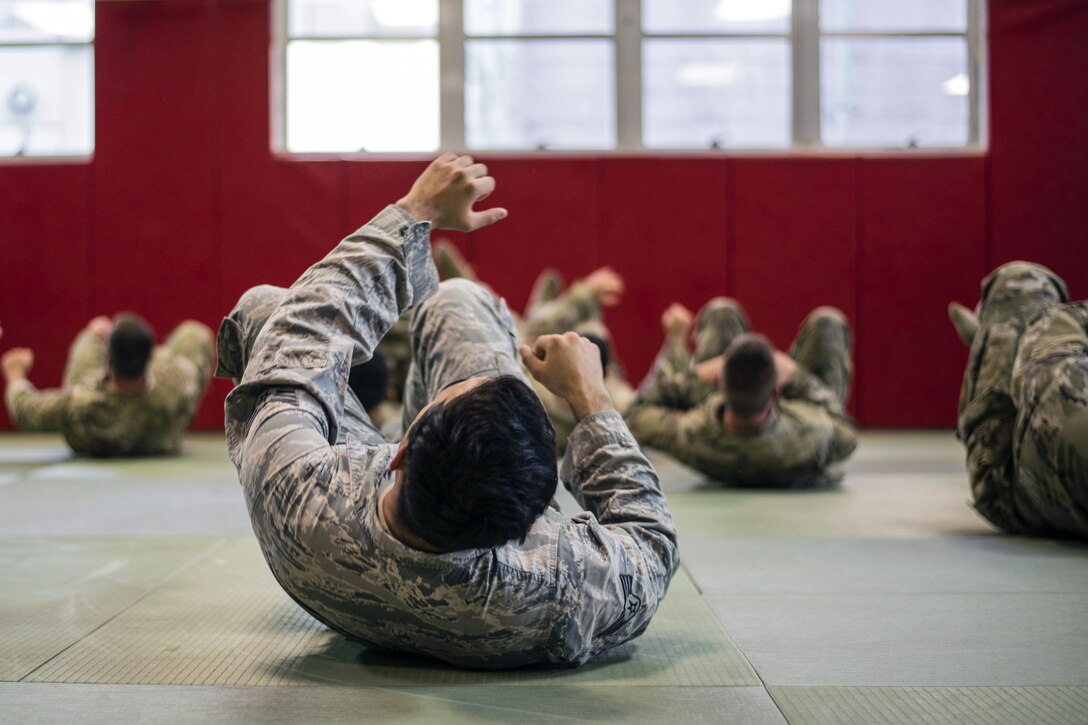 U.S. and Japanese forces roll on their backs during a conditioning drill.