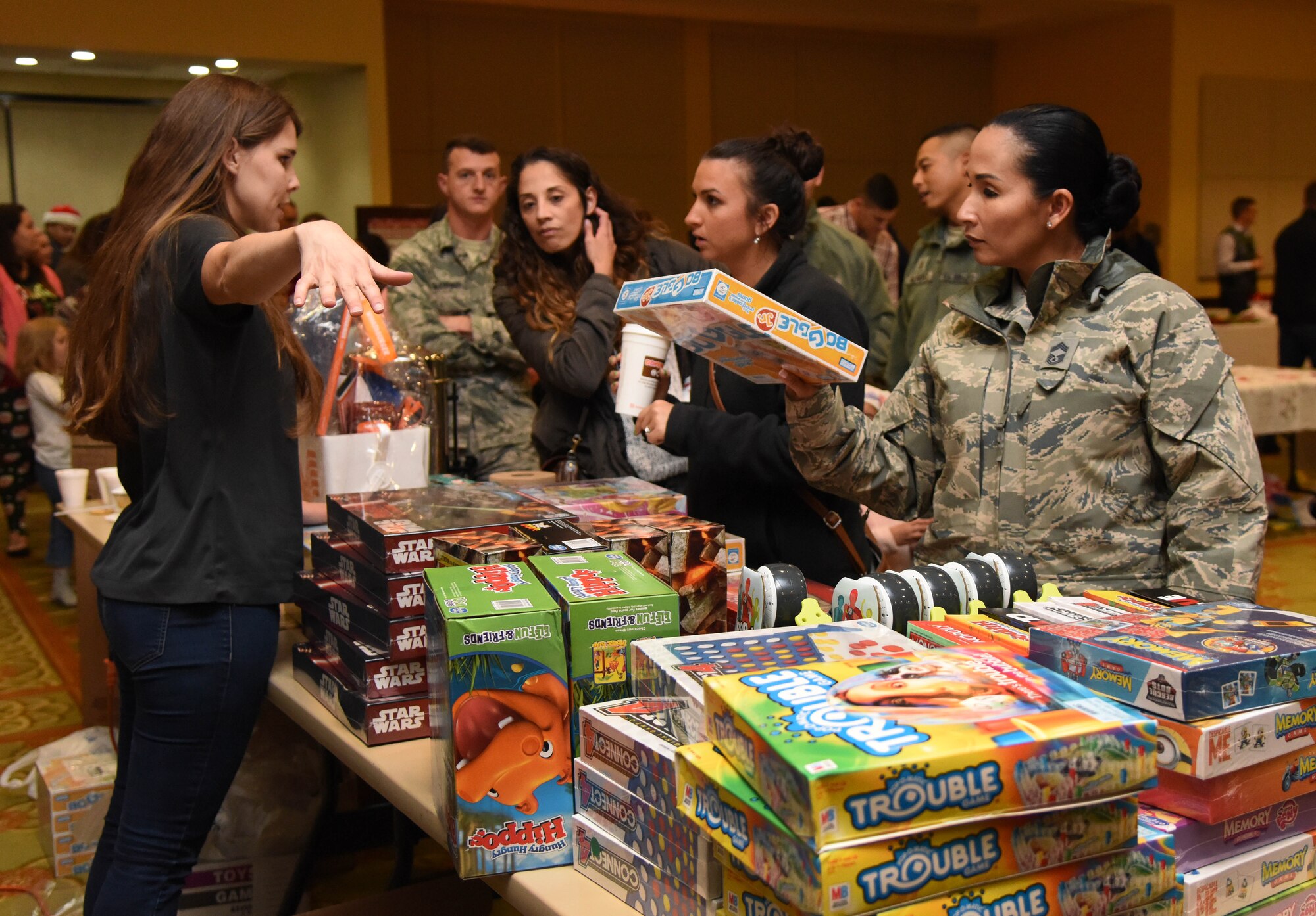 Heather Altman, spouse of Staff Sgt. Gabriel Altman, 335th Training Squadron instructor, assists Keesler families at the gift table during Keesler’s annual Christmas celebration at the Bay Breeze Event Center Dec. 7, 2017, on Keesler Air Force Base, Mississippi. The event, hosted by Outdoor Recreation, included cookie and ornament decorating, games and visits with Santa. (U.S. Air Force photo by Kemberly Groue)
