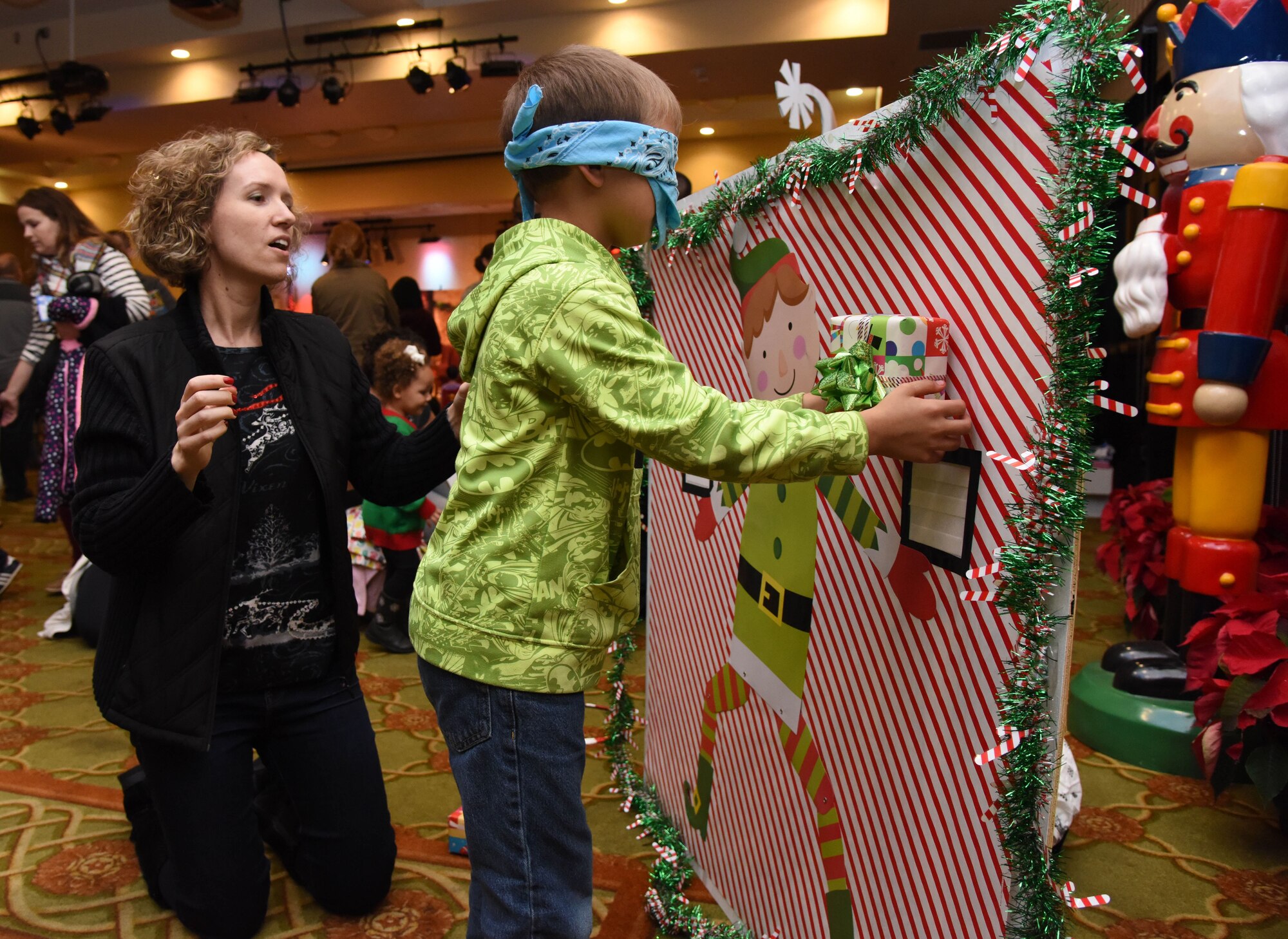 First Lt. Davina Armbruster, 81st Inpatient Operation Squadron labor and delivery nurse, assists Ryan Hoskins, son of 1st Lt. Nina Hoskins, 81st Surgical Operations Squadron operating room nurse, with a festive game during Keesler’s annual Christmas celebration at the Bay Breeze Event Center Dec. 7, 2017, on Keesler Air Force Base, Mississippi. The event, hosted by Outdoor Recreation, included cookie and ornament decorating, games and visits with Santa. (U.S. Air Force photo by Kemberly Groue)