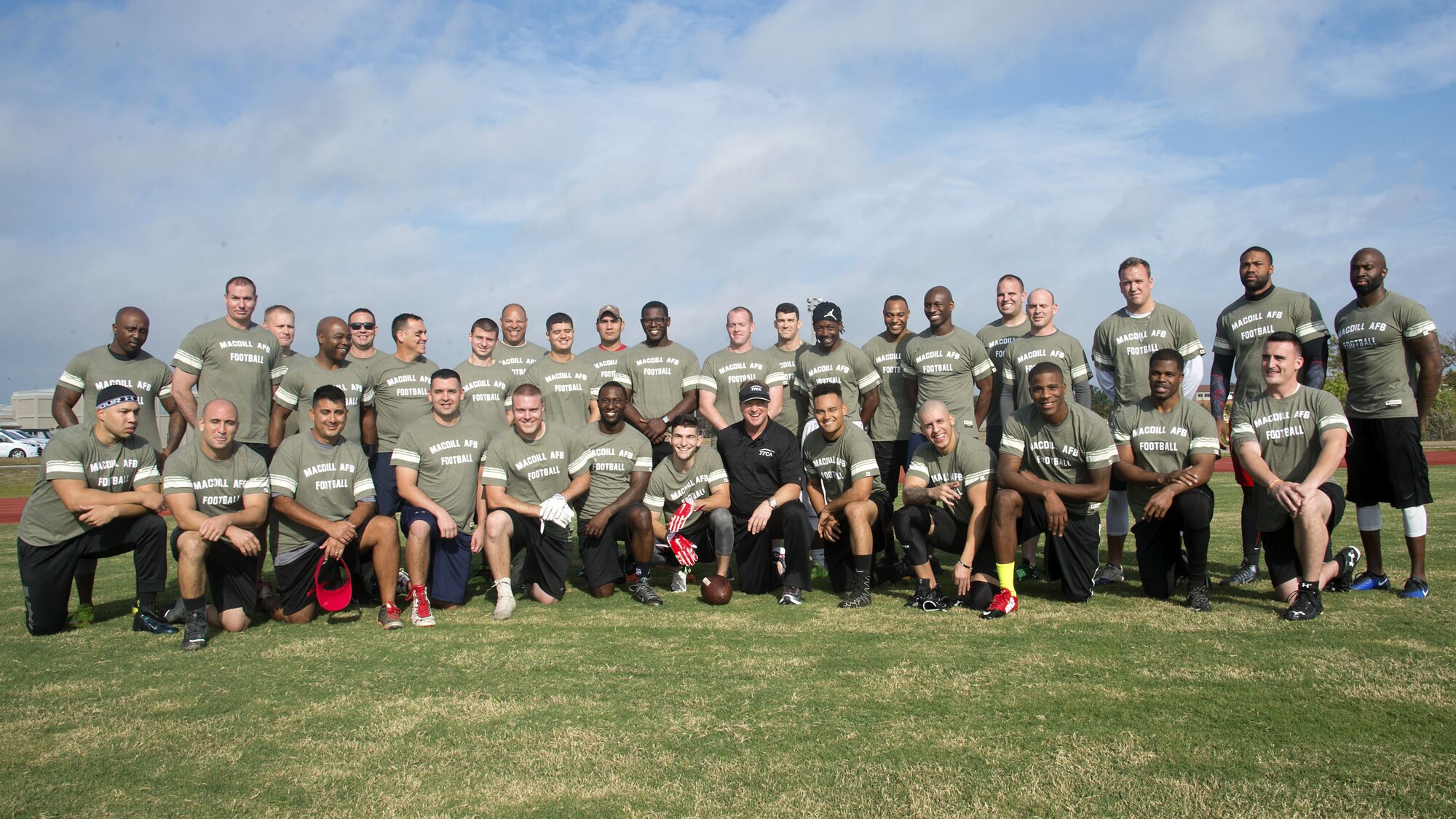 Service members pause for a group photo with Jon Gruden (center), a Monday Night Football color analyst, at MacDill Air Force Base, Fla., Dec. 8, 2017. Gruden hosted a football camp at MacDill to show appreciation to service members.