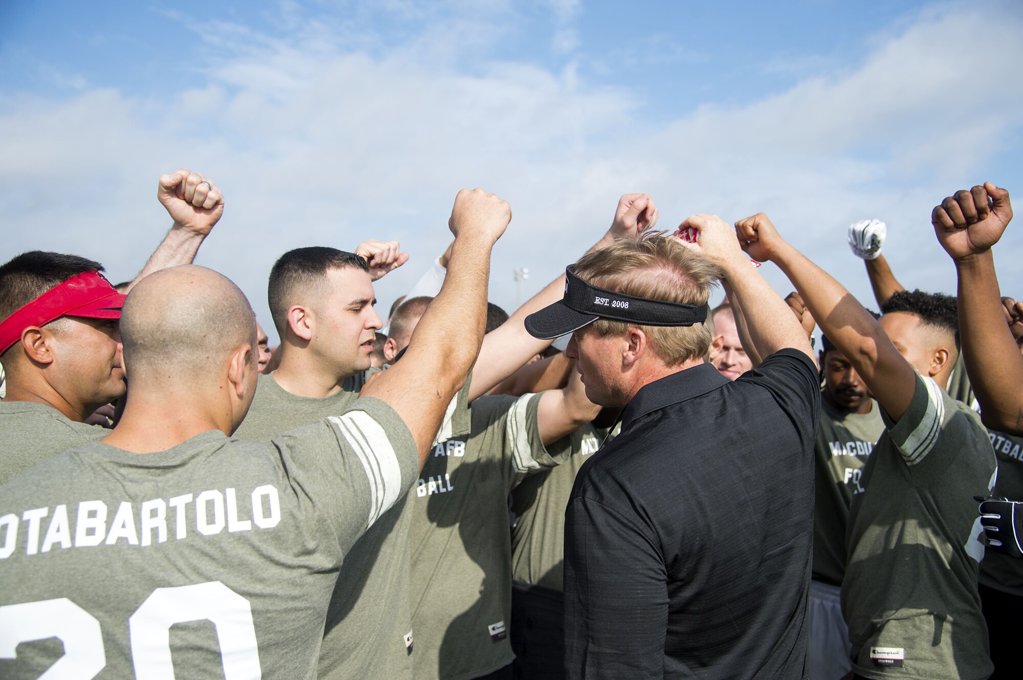 Service members huddle around Jon Gruden, a Monday Night Football color analyst, during a football camp at MacDill Air Force Base, Fla., Dec. 8, 2017. Gruden gave the participants a pep talk about communication and execution before practicing plays.