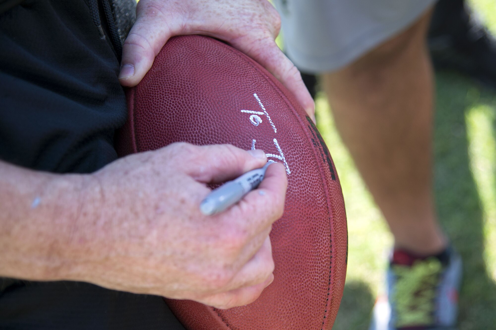 Jon Gruden, a Monday Night Football color analyst, autographs a football for a service member at MacDill Air Force Base, Fla., Dec. 8, 2017. Gruden signed autographs and took photos with service members after teaching them how to effectively work together to accomplish one goal.
