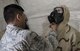 Senior Airman Co Nguyen, 92nd Civil Engineer Squadron logistics journeyman, helps an airman properly dawn a M50 gas mask during an exercise, at Fairchild Air Force Base, Washington Nov. 30, 2017. Mobility Airmen are trained to be wary of potential CBRN environments, as they can appear normal to naked eye. (U.S. Air Force photo/ Senior Airman Sean Campbell)