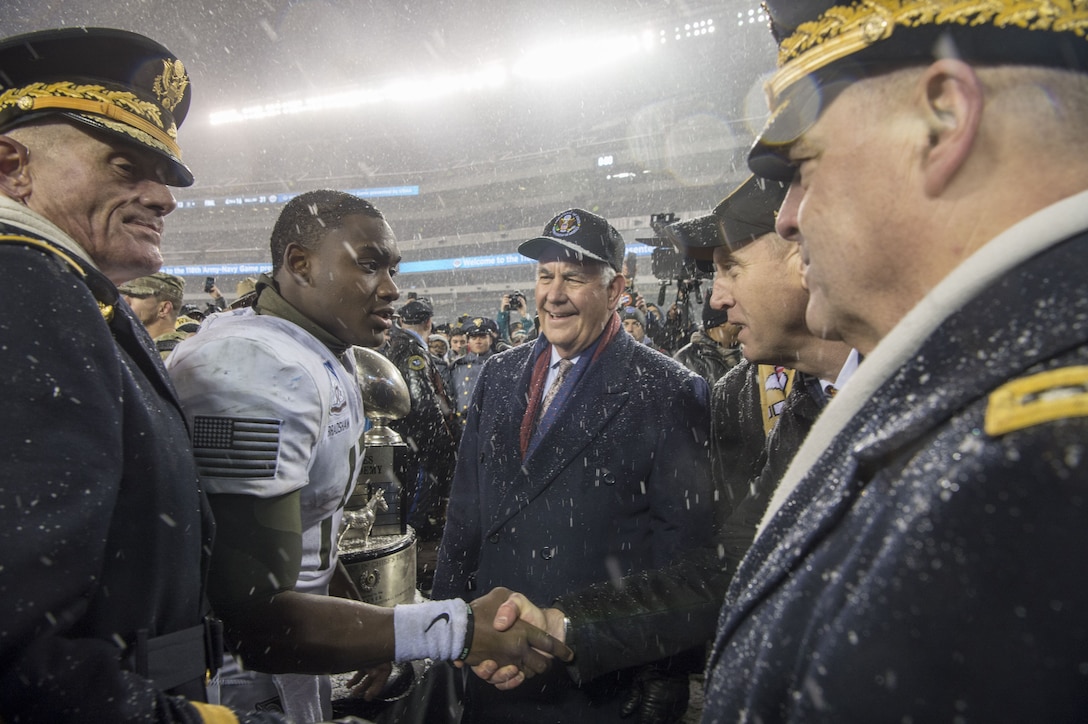 The deputy defense secretary shakes hands with Army's quarterback on a football field.