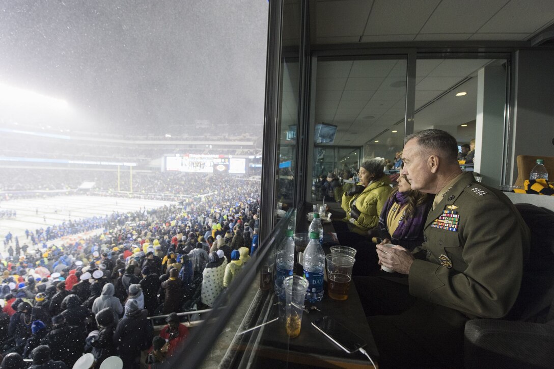 The chairman of the Joint Chiefs watches the Army-Navy football game with wounded warriors.