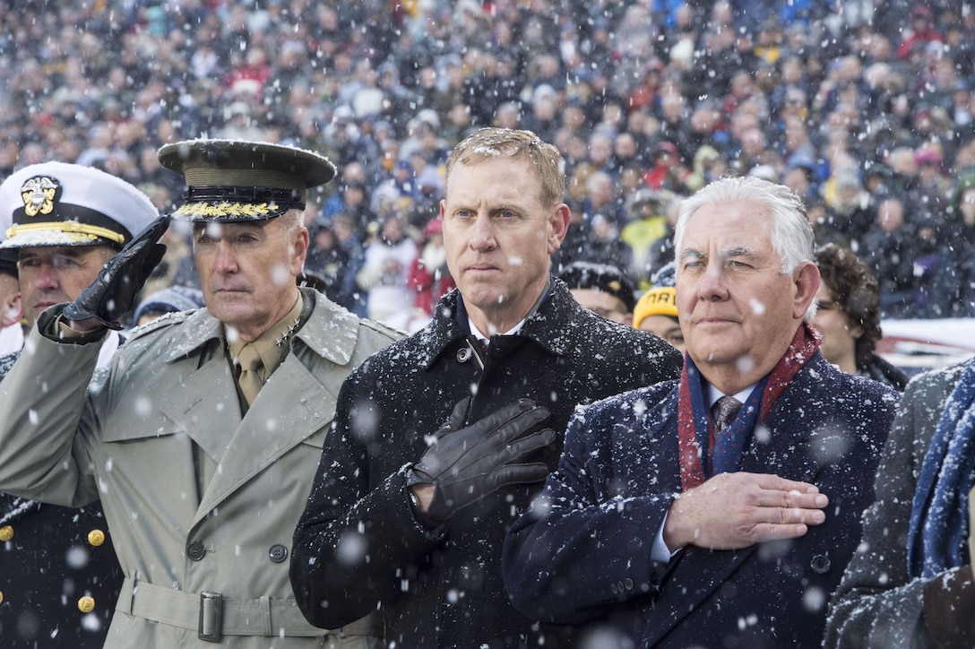 Defense leaders salute or stand at attention during the national anthem.