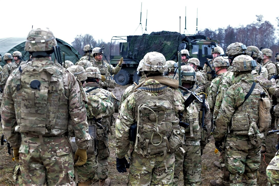 A group of soldiers listens to another soldier.