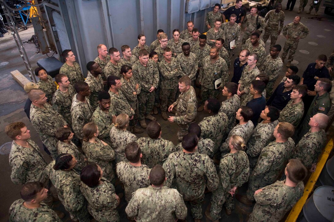 Sailors meet with an Army general in the well deck of an amphibious ship