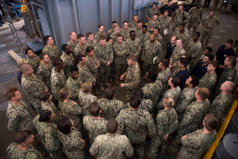 Sailors meet with an Army general in the well deck of an amphibious ship