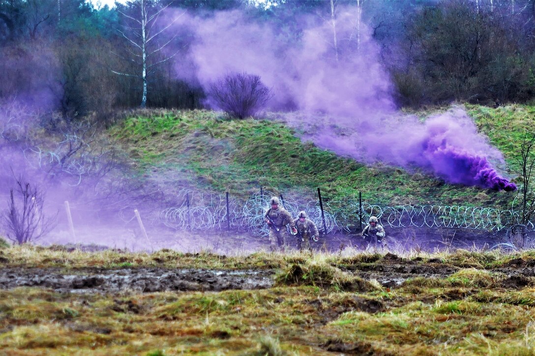 Soldiers run through purple smoke.